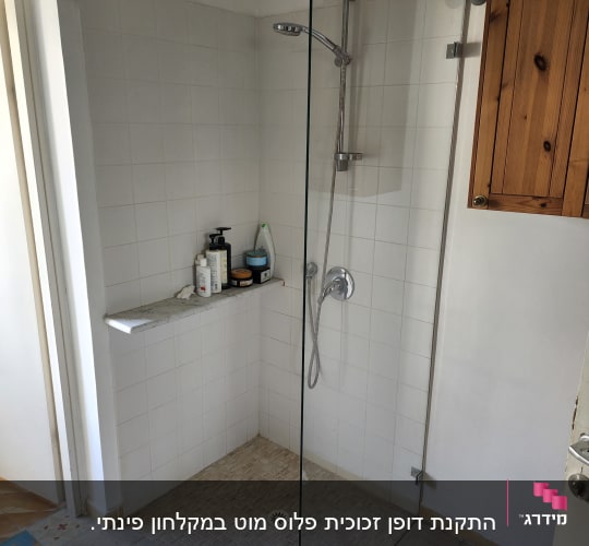מקלחת עם דלת זכוכית, ראש מקלחת ומוצרי טיפוח